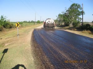 Truck spraying new asphalt on dirt road