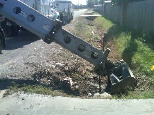 Backhoe digging trench next to fence