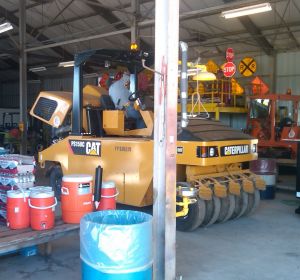 Man driving large yellow construction truck out of a storage building