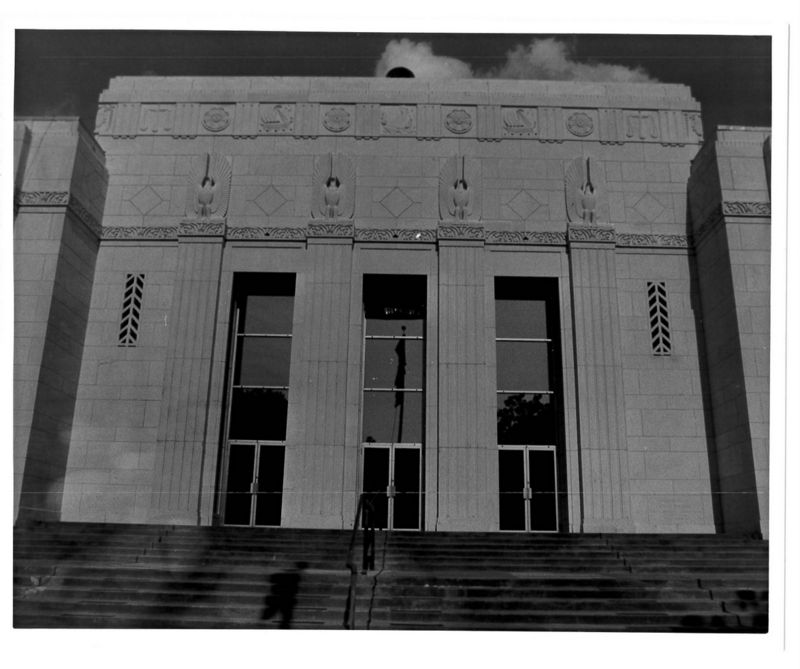 Black and white photo of white building with stairs in front of it.